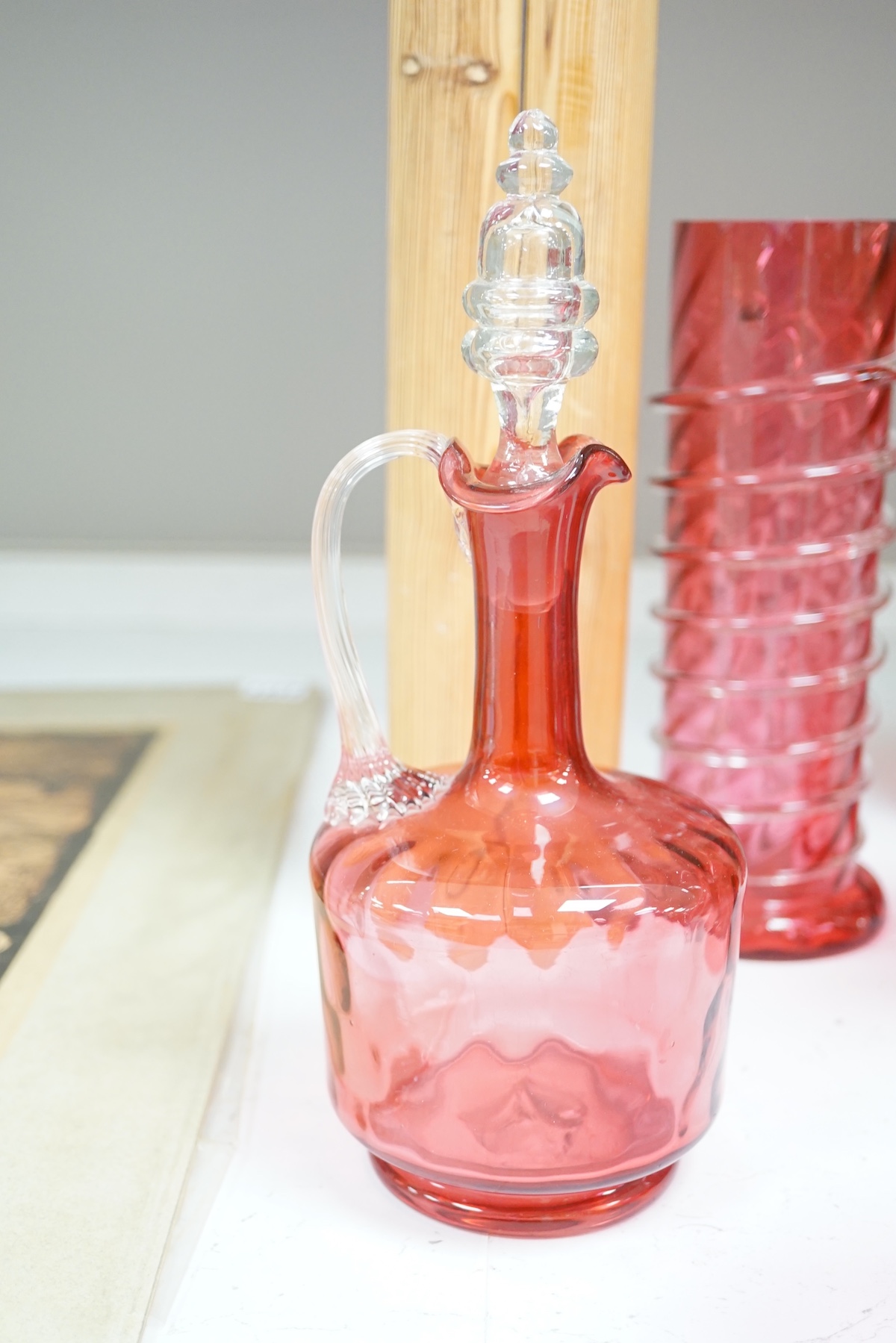 A quantity of cranberry glassware to include pair of vases with trailed decoration, jugs and an oil lamp, largest 38cm high. Condition - fair, some chipping